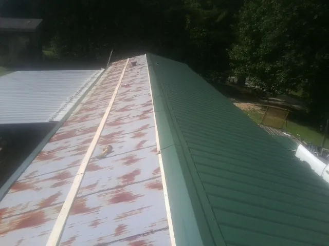 Old rusted panels beside newly installed green metal roofing — Wind Damage Roof Repair by Roofing Brothers in Sebago