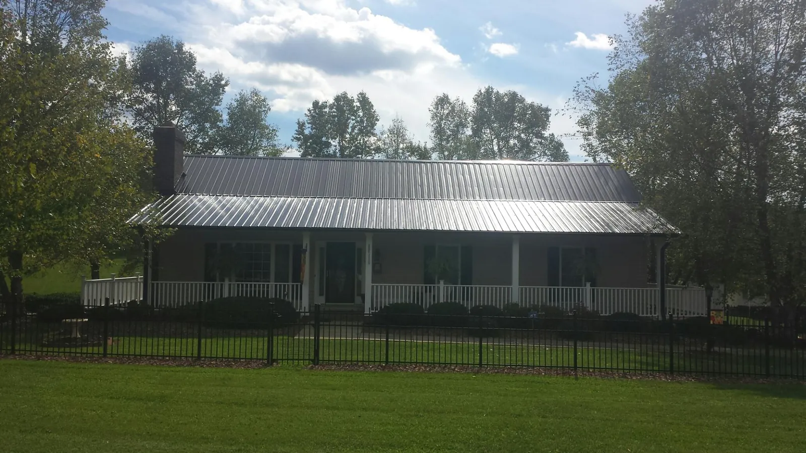 Gray metal roof on a brick ranch with a full width front porch — Gutter Guard Installation work by our crew in Sebago