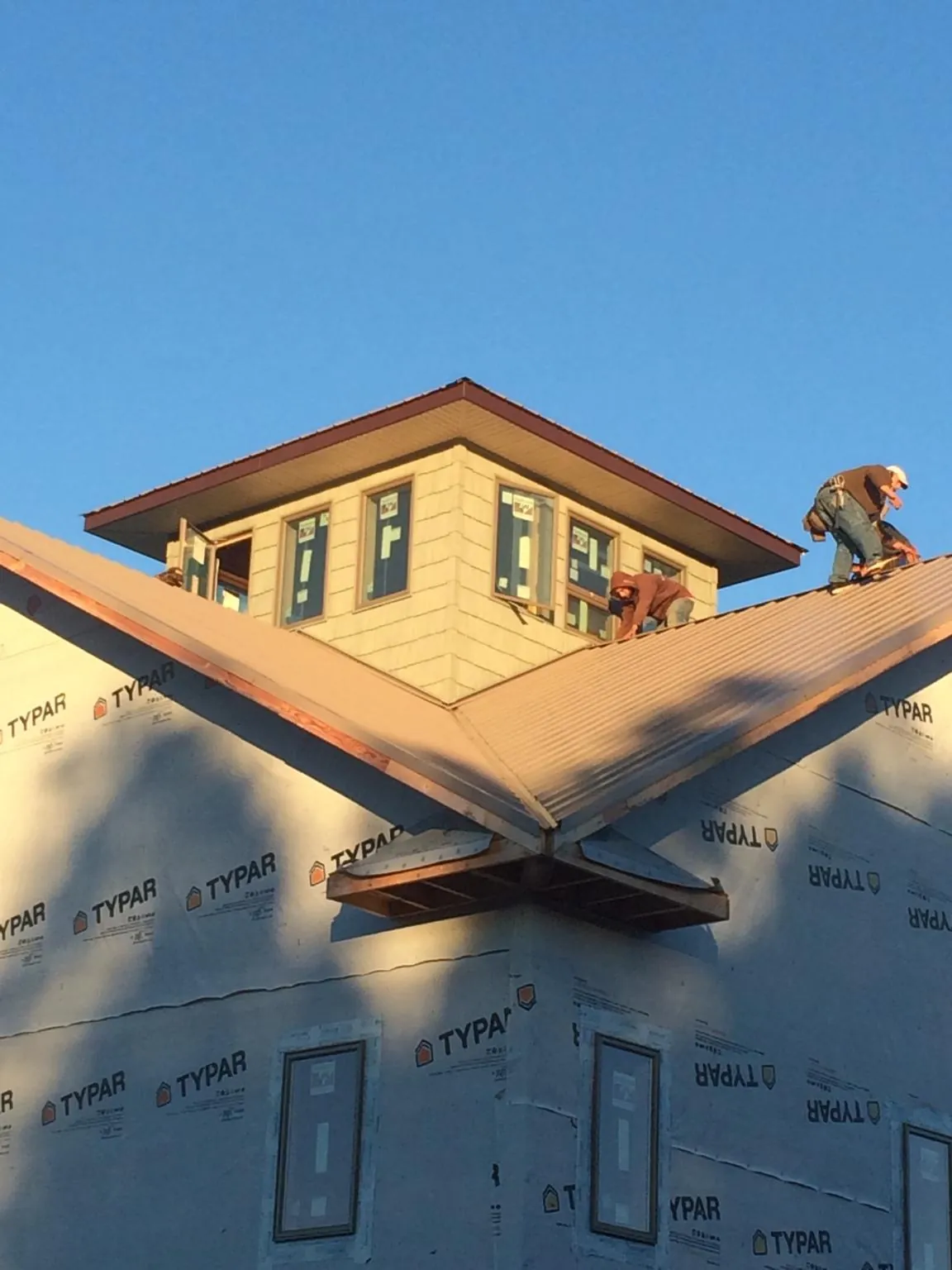 Roofers working around a rooftop cupola on a new metal roof at sunset — Roof Waterproofing in Sebago by Roofing Brothers